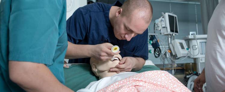 henkilöt hoitamassa potilasta esittävää nukkea.