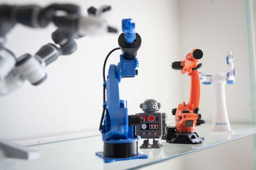 Lasipöydällä rivissä robottilelu ja erilaisia robottityövälineitä.