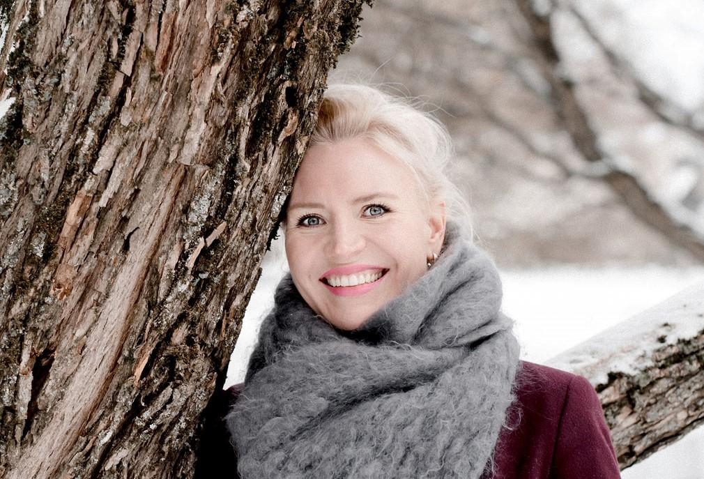 Johanna Linner Matikka nojaamassa puuhun talvella.