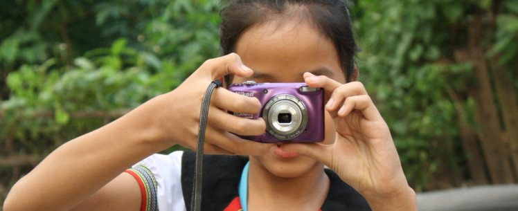 Tyttö kuvaa kameralla kameraa kohti.