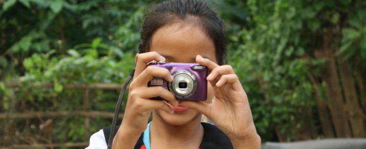 Tyttö kuvaa kameralla kameraa kohti.